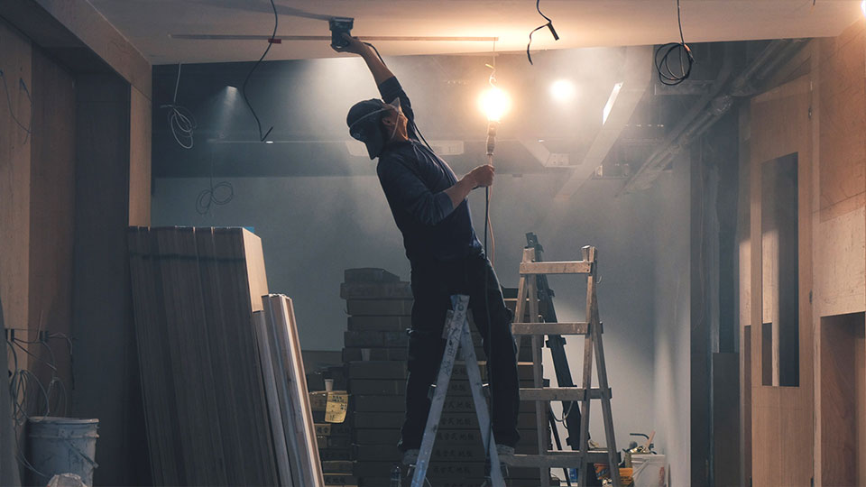 Man on ladder fixing drywall